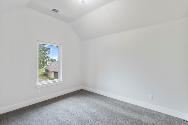 carpeted spare room featuring vaulted ceiling