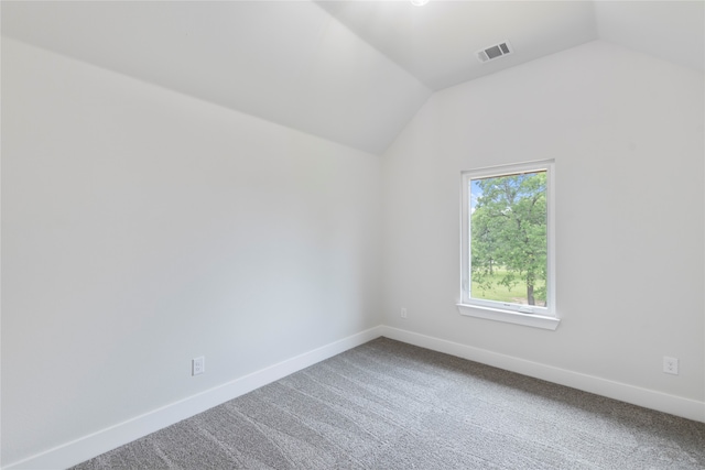 carpeted empty room featuring vaulted ceiling