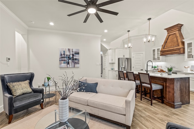 living room featuring sink, light wood-type flooring, vaulted ceiling, ceiling fan with notable chandelier, and ornamental molding