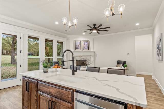 kitchen with sink, a premium fireplace, dishwasher, light hardwood / wood-style floors, and hanging light fixtures