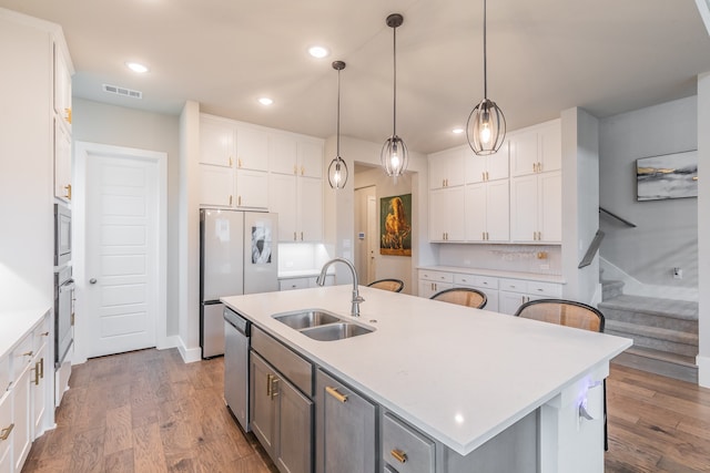 kitchen with white cabinetry, sink, hanging light fixtures, an island with sink, and hardwood / wood-style flooring