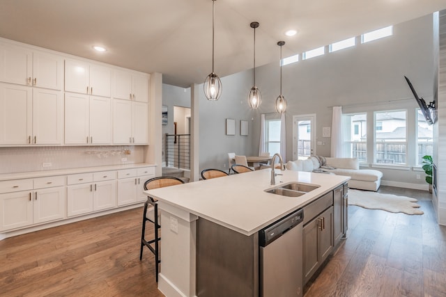 kitchen featuring white cabinets, sink, wood-type flooring, dishwasher, and hanging light fixtures