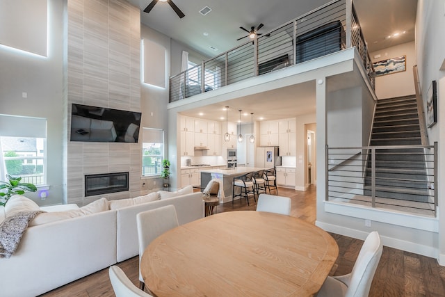 dining room with a fireplace, a healthy amount of sunlight, a high ceiling, and hardwood / wood-style flooring