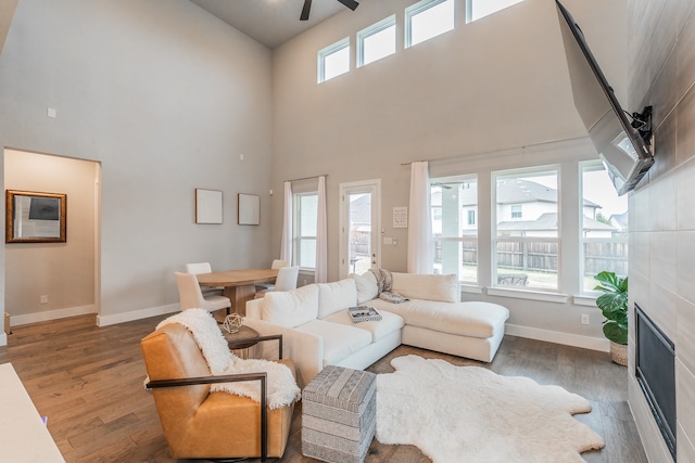 living room with a towering ceiling, hardwood / wood-style flooring, and a healthy amount of sunlight