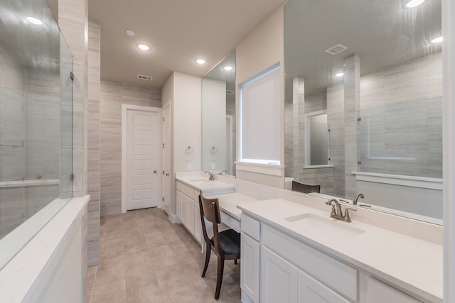 bathroom with a tile shower, vanity, tile patterned floors, and tile walls