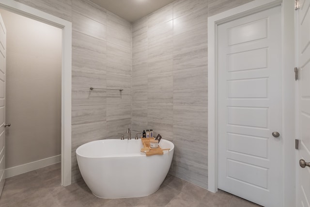 bathroom featuring tile patterned floors, a bath, and tile walls