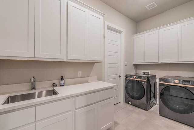 laundry area with light tile patterned flooring, cabinets, independent washer and dryer, and sink