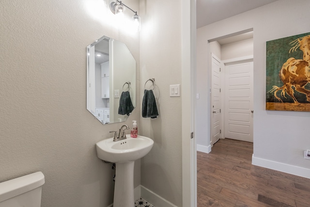 bathroom with toilet, wood-type flooring, and sink