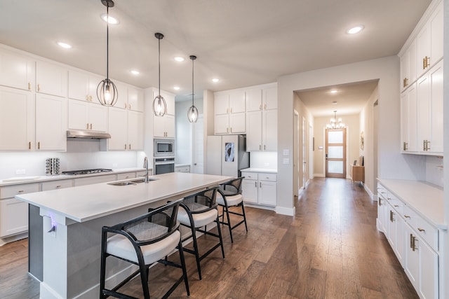 kitchen with stainless steel appliances, dark wood-type flooring, sink, a center island with sink, and white cabinets