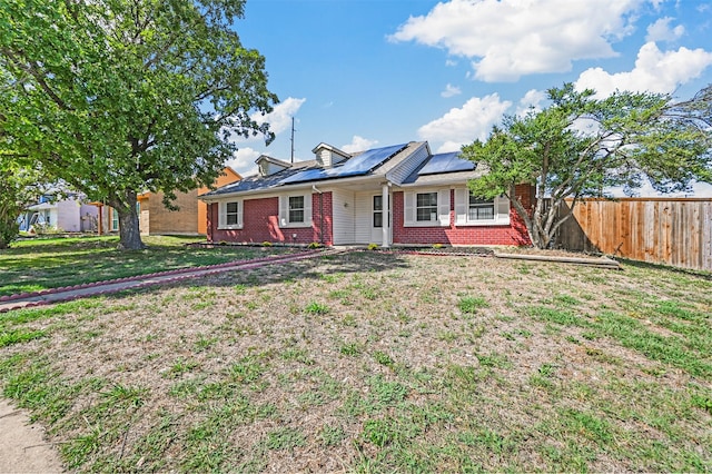 ranch-style home featuring a front yard and solar panels