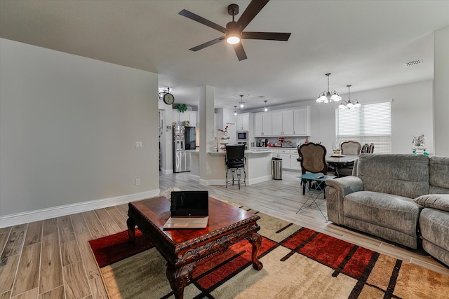 living room with light hardwood / wood-style flooring and ceiling fan with notable chandelier