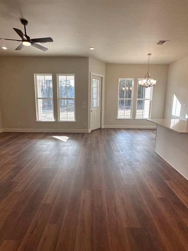 unfurnished living room with dark wood-style flooring, recessed lighting, visible vents, baseboards, and ceiling fan with notable chandelier