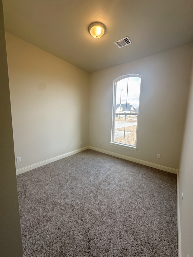 carpeted empty room with visible vents and baseboards