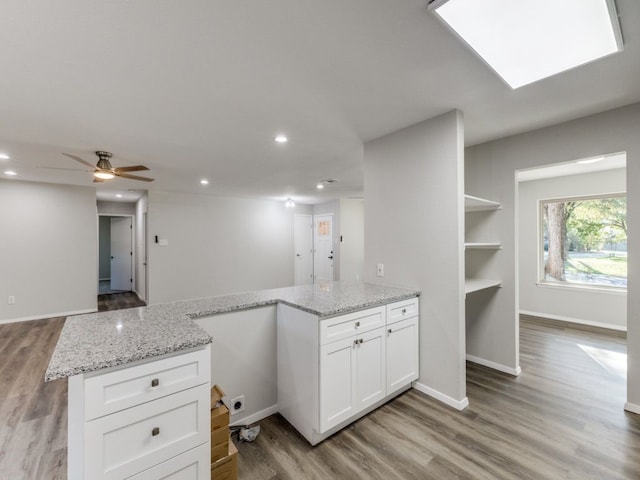 kitchen featuring light wood-type flooring, white cabinetry, and light stone counters