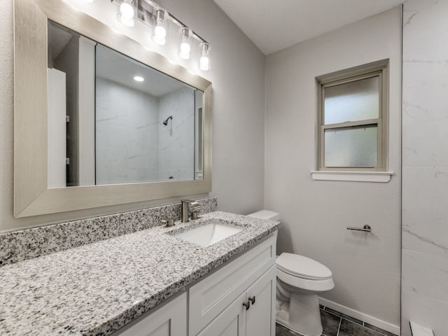 bathroom with a tile shower, vanity, toilet, and tile patterned floors