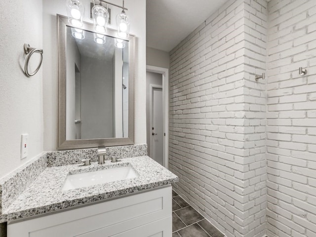 bathroom with tile patterned flooring, vanity, and brick wall