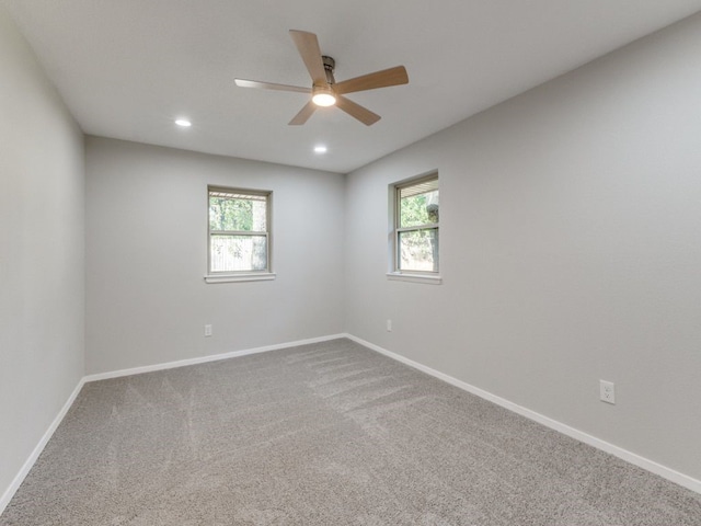 carpeted spare room featuring a wealth of natural light and ceiling fan