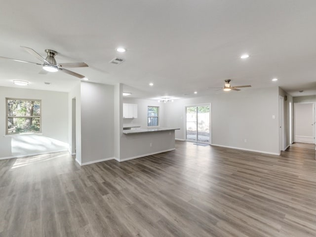 unfurnished living room with plenty of natural light, ceiling fan, and wood-type flooring