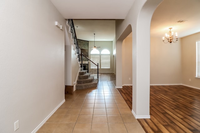 hall featuring light tile patterned floors and a notable chandelier