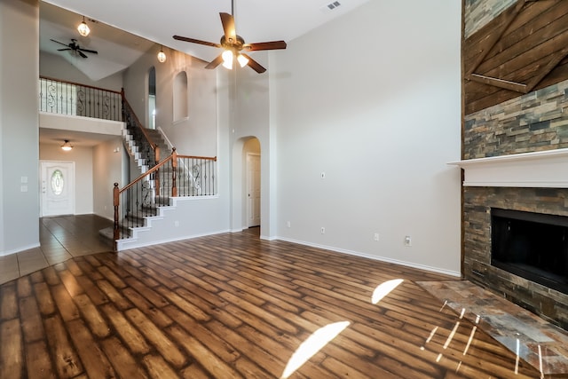 unfurnished living room with dark hardwood / wood-style floors, high vaulted ceiling, and a stone fireplace