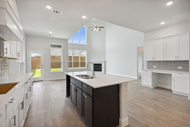 kitchen featuring white cabinetry, sink, and an island with sink