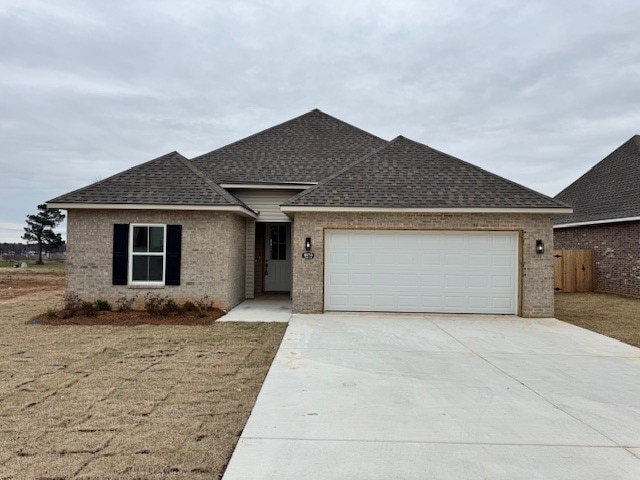 ranch-style house featuring a garage, a shingled roof, concrete driveway, and brick siding