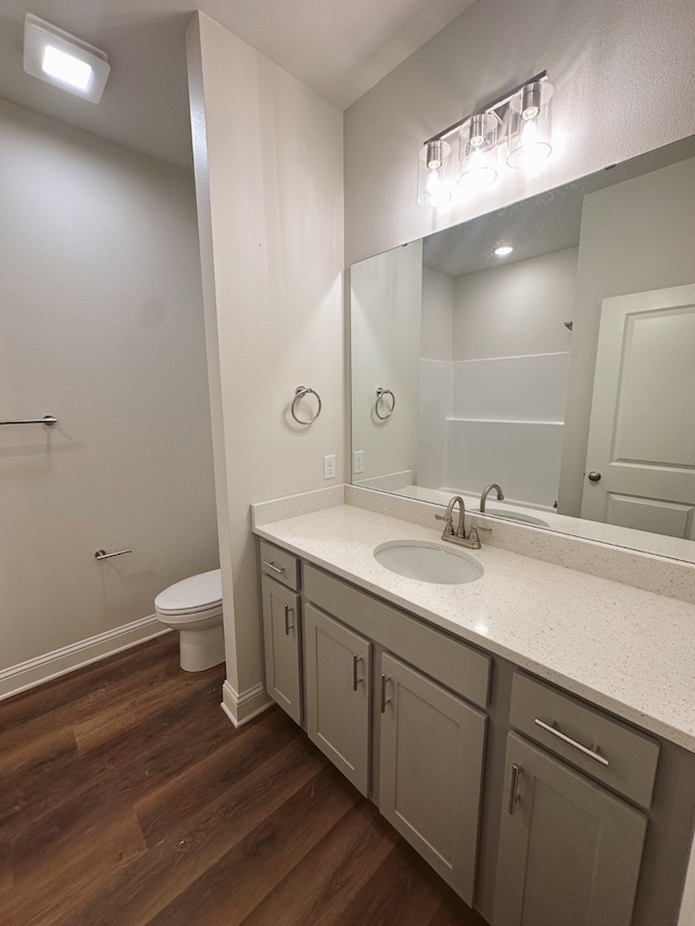 bathroom featuring toilet, vanity, baseboards, and wood finished floors