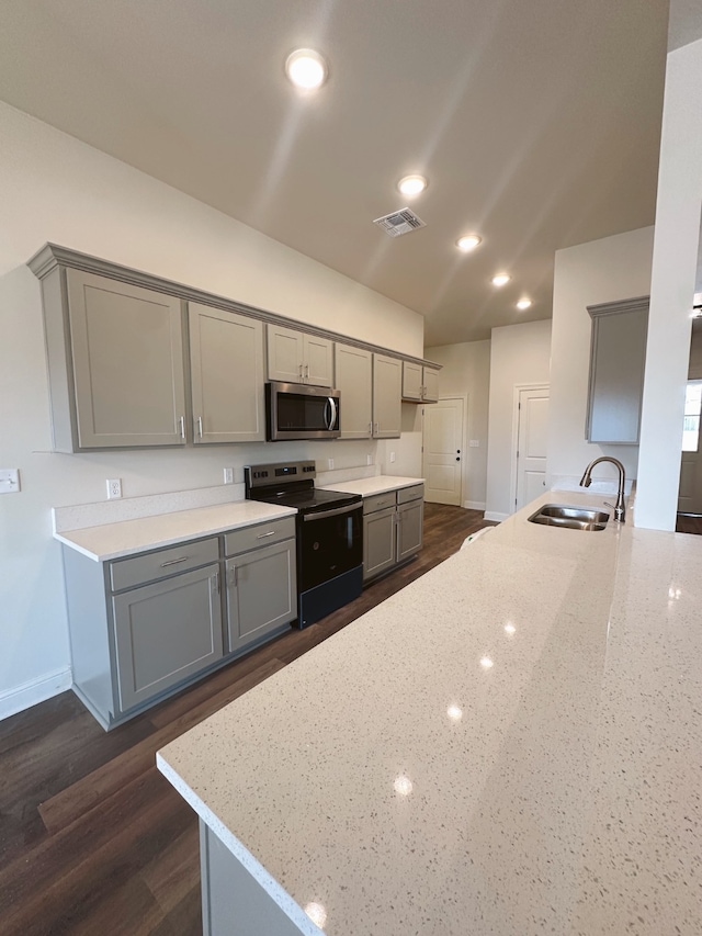 kitchen with black electric range, light stone counters, stainless steel microwave, and gray cabinets