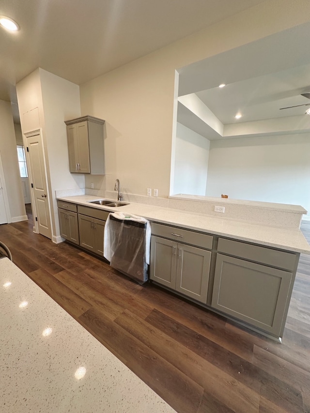 kitchen with dishwasher, dark wood-style floors, a peninsula, gray cabinetry, and a sink