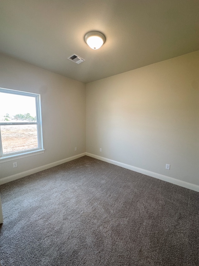 unfurnished room featuring dark carpet, visible vents, and baseboards