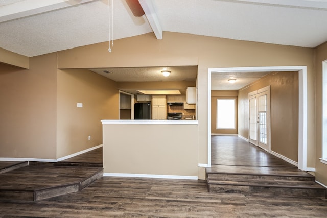 interior space with a textured ceiling, vaulted ceiling with beams, dark hardwood / wood-style floors, and black appliances