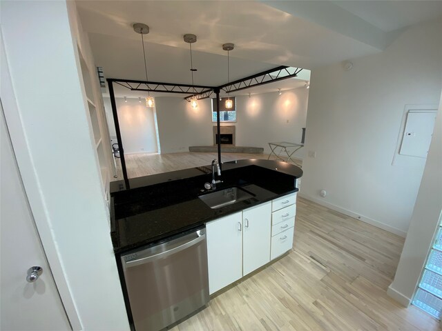 kitchen with light wood-type flooring, stainless steel dishwasher, sink, white cabinetry, and hanging light fixtures