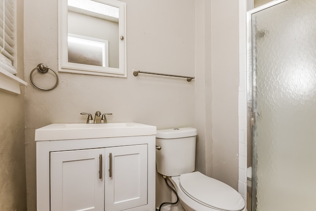 bathroom featuring walk in shower, vanity, and toilet