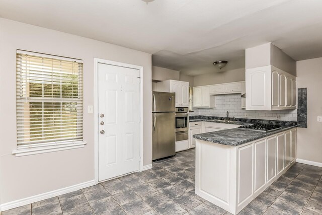 kitchen featuring kitchen peninsula, decorative backsplash, stainless steel appliances, sink, and white cabinets