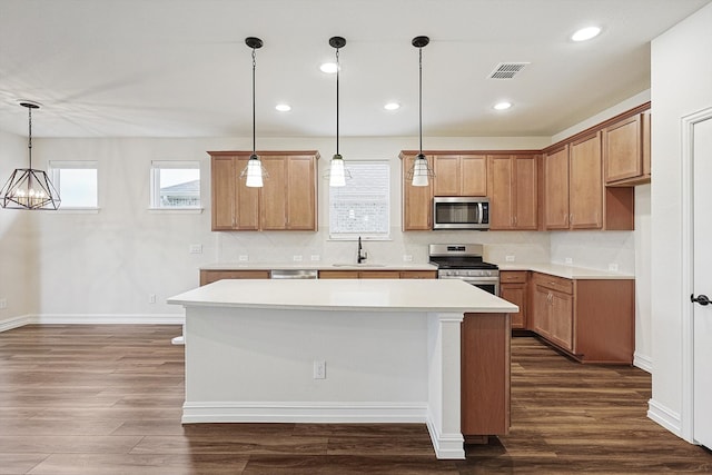 kitchen with appliances with stainless steel finishes, a center island, sink, and decorative light fixtures