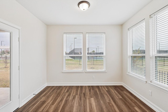 empty room with dark hardwood / wood-style floors and a wealth of natural light