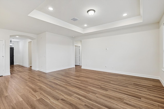 unfurnished room with a raised ceiling, crown molding, and hardwood / wood-style flooring