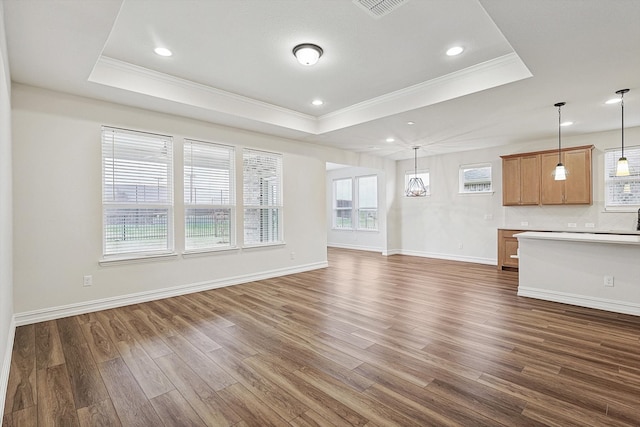 unfurnished living room with a tray ceiling, a wealth of natural light, and dark wood-type flooring