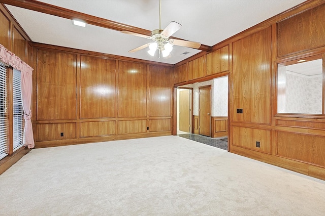 unfurnished bedroom with crown molding, carpet floors, ceiling fan, and wood walls