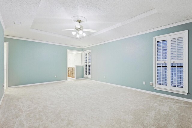 carpeted empty room featuring ceiling fan, crown molding, a raised ceiling, and a textured ceiling