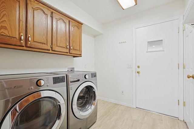 clothes washing area with cabinets, washing machine and clothes dryer, and light wood-type flooring