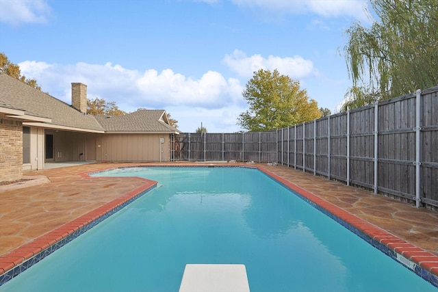 view of swimming pool with a diving board and a patio