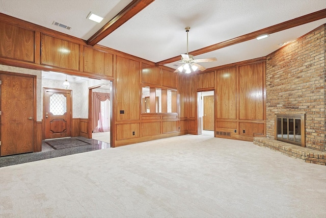 unfurnished living room with a fireplace, beam ceiling, carpet, and wood walls