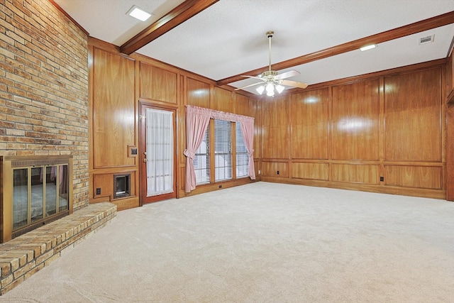 unfurnished living room featuring beamed ceiling, wooden walls, a fireplace, and carpet