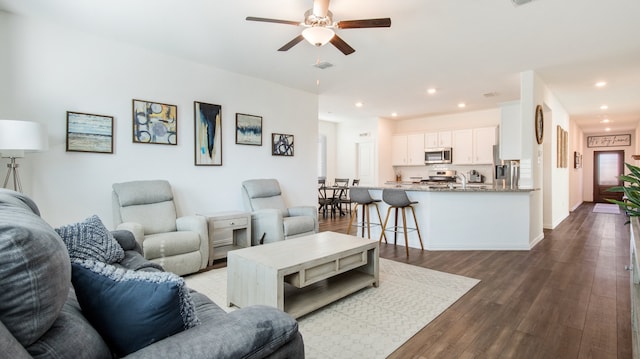 living room featuring ceiling fan, sink, and dark wood-type flooring