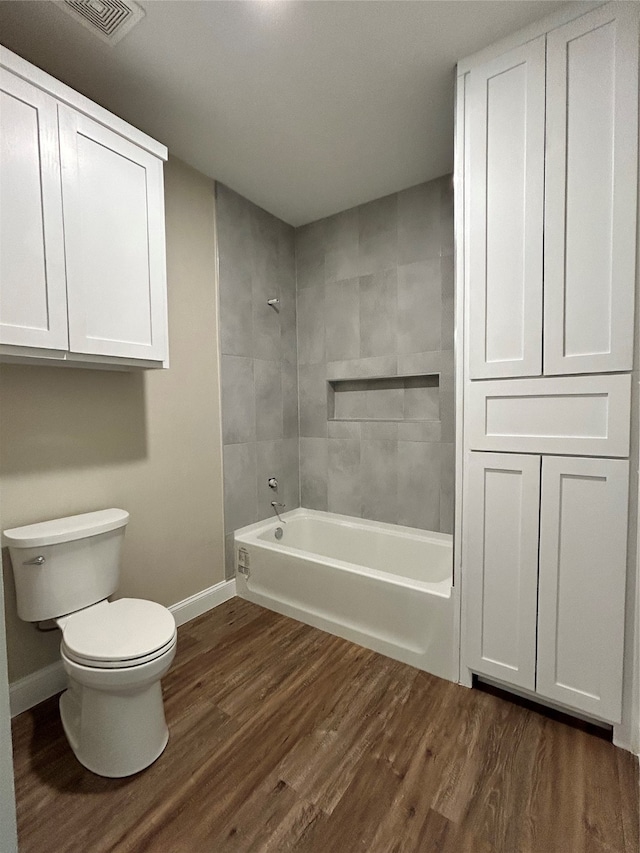 bathroom featuring toilet, hardwood / wood-style floors, and tiled shower / bath