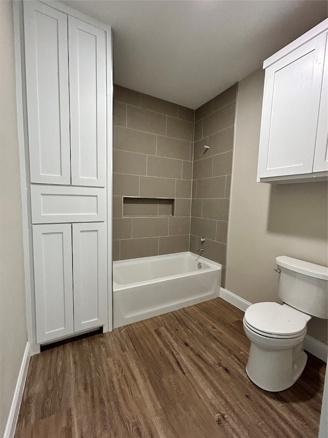 bathroom with wood-type flooring, toilet, and tiled shower / bath