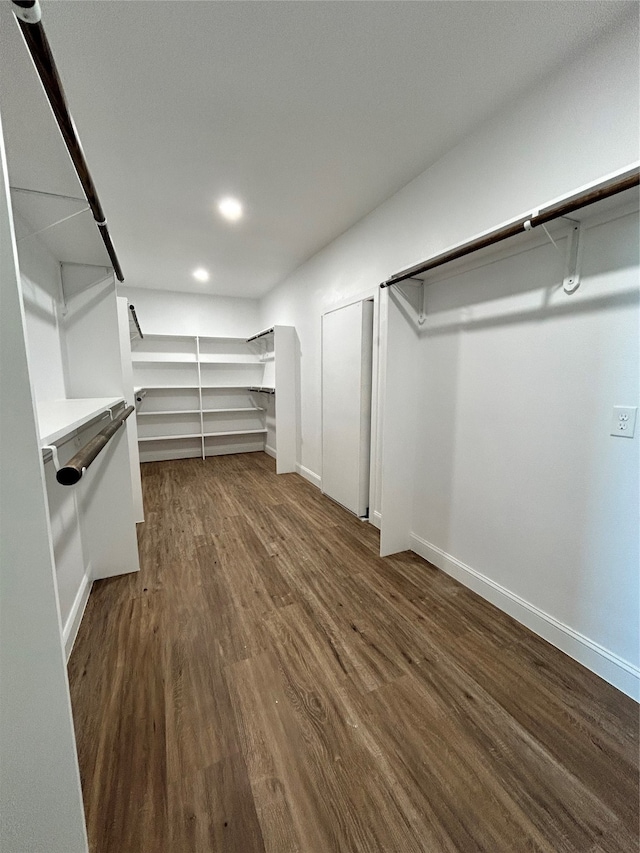 walk in closet with dark wood-type flooring