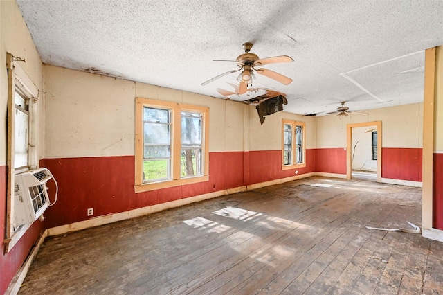 empty room featuring ceiling fan, cooling unit, dark wood-type flooring, and a textured ceiling