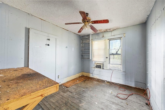 spare room featuring wood-type flooring, a textured ceiling, ceiling fan, and wooden walls